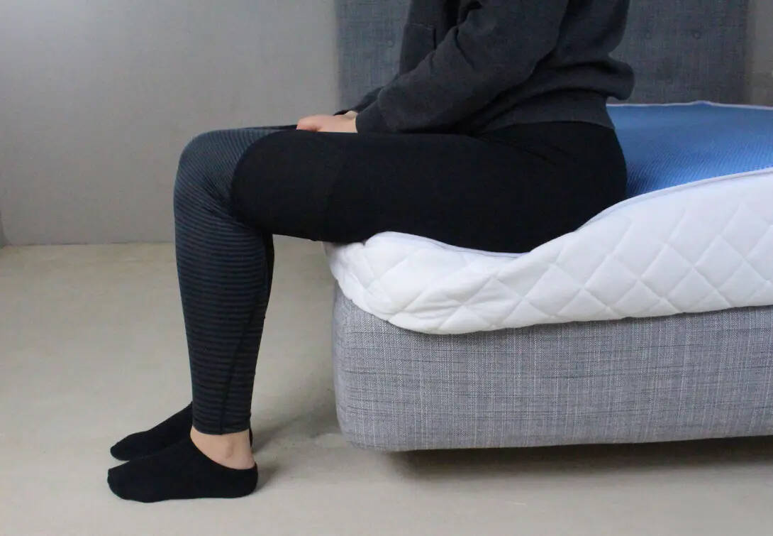 Probeschläferin sitzend auf der Kante der Weltbett Matratze